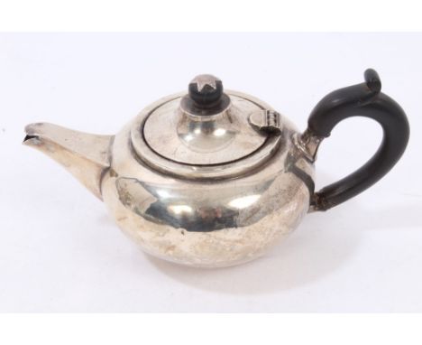 George V silver bachelors teapot of compressed form, with ebony loop handle and hinged conical cover with silver / ebony fini