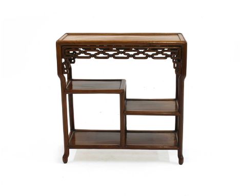 A Chinese hardwood side table, 20th century, the rectangular top above a pierced frieze and stepped shelves, on turned suppor