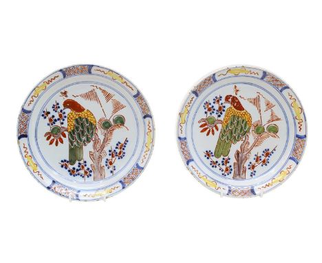 A pair of Dutch Delft shallow bowls, c.1780, each painted with a bird perched on a branch within a panelled diaper border, pa