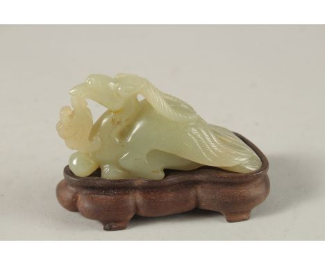 A CHINESE CARVED JADE FIGURE OF A MYTHICAL CREATURE on a wooden stand, jade 10cm long.