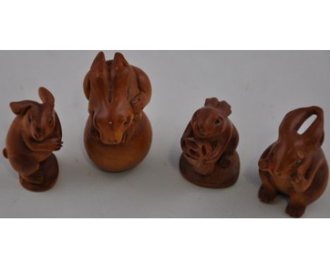 Four hardwood netsuke/ carvings modelled as hares