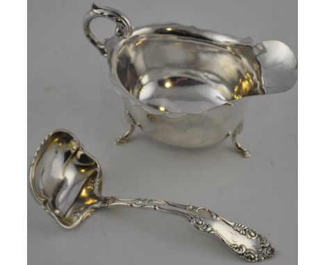 A silver sauce boat, Birmingham, with an ogee edge and raised on three pad feet, together with an American white metal ladle,