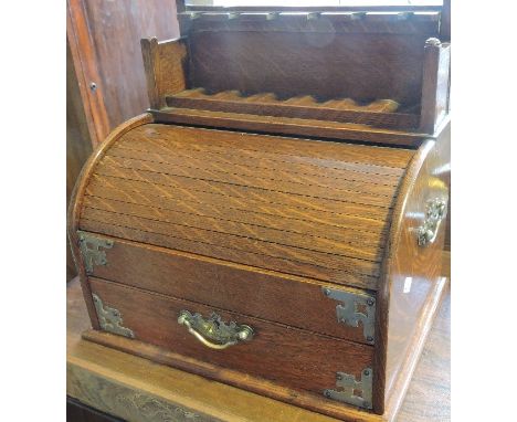 A late 19th century oak and white metal mounted smoker's compendium, with a pipe rack above a tambour linked to a drawer and 
