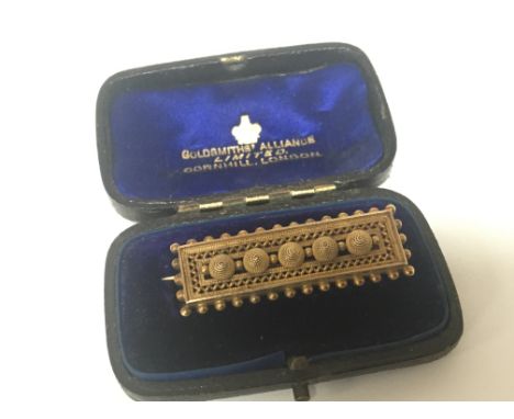An unmarked Vintage gold brooch of rectangular shape with raised decoration in a fitted box.