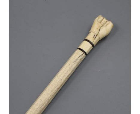 A 19th century scrimshaw whalebone and marine ivory walking stick, the handle carved as a clenched fist with baleen collars l