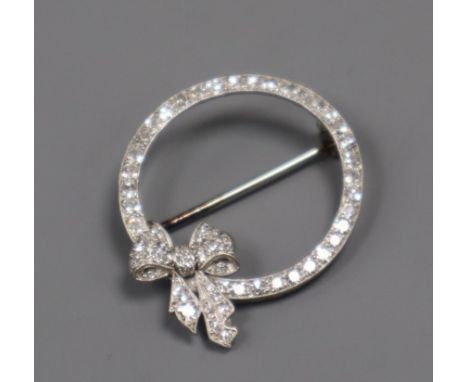 A mid 20th century white metal and diamond set openwork circular brooch with ribbon bow motif, 31mm.