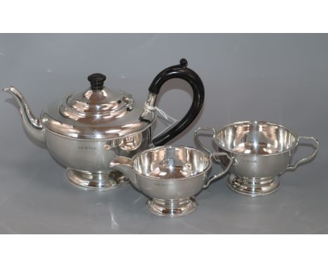 A George V silver three-piece tea service, of circular bead-edged form, Birmingham, 1931, gross 20 oz.