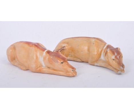Two mid-late nineteenth century Staffordshire ceramic greyhounds, each reclining with a tan coat and single dark stripe along