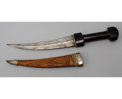 A late 19th century jambiya, the ebony handle over curved steel blade with raised medial ridge, in white metal mounted carved