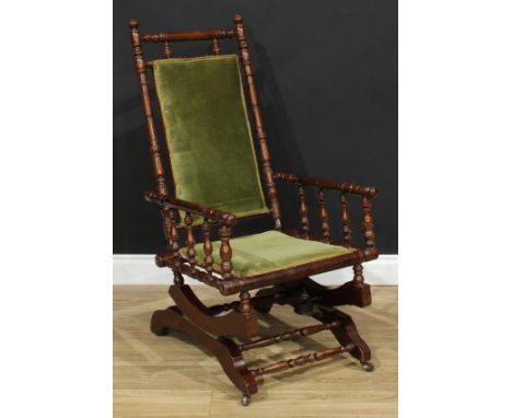 An early 20th century 'American' spring rocking chair, stuffed-over upholstery, the frame ring-turned throughout, 105.5cm hig