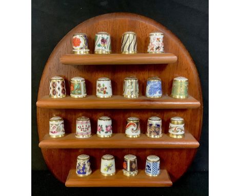 A set of twenty Royal Crown Derby thimbles, assorted patterns, on a wooden wall rack 