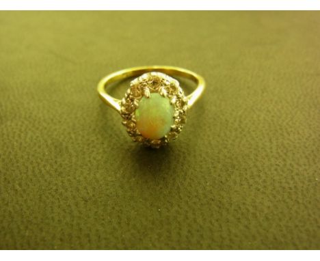 An opal and diamond cluster ring - The oval opal within a single-cut diamond surround - Estimated total diamond weight 0.30ct