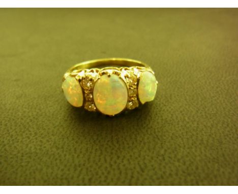 A 1970s  18ct gold opal and diamond dress ring - The graduated oval opals to the brilliant-cut diamond spacer lines - Hallmar