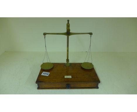 A set of Victorian brass and mahogany balance scales with a base drawer containing assorted weights bearing an ivorine plaque