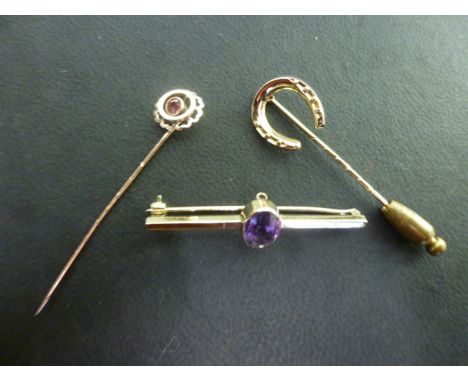 A 9ct gold and amethyst bar brooch, a 9ct gold horseshoe stick pin and a 9ct pink stone stick pin