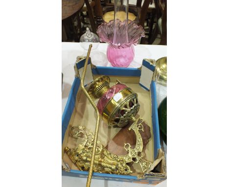 A brass wall mounted oil lamp with cranberry glass reservoir and shade, together with a bell-shaped glass smut cover.