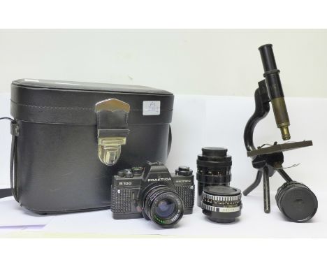 A Praktica B100 electronic film camera, lenses and accessories in a fitted case and a microscope