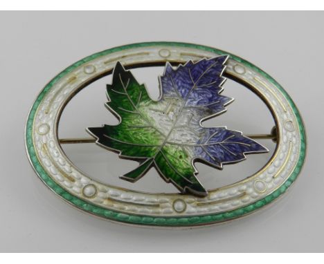 An unusual Canadian silver and enamel oval sash brooch, guilloche enamelled in blue, white, and green, shaped as a maple leaf