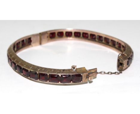 A 9ct gold mounted multi-stone garnet bangle with hinge and clasp, width approx 7cm, approx 18g.