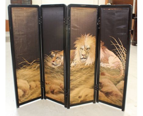 An early 20th century Japanese black lacquer four-panel folding screen, each silk panel with woven images of a lion and lione