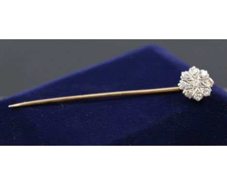 A white and yellow metal stick pin with floral decoration set with nine diamonds.