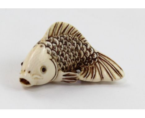 A Meiji period ivory netsuke carved in the form of a swimming koi carp and with red signature to the base, length 5.5cm.