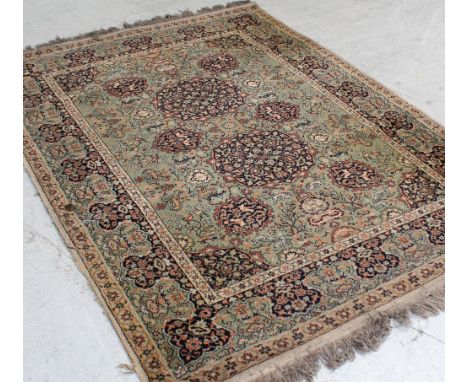A Persian-style green ground rug decorated with flora and animals, approx 149 x 205cm. CONDITION REPORT There is a burn mark 