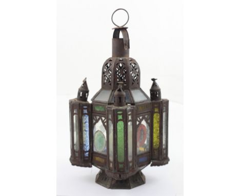 A late 19th/early 20th century Moroccan metal lamp with glass panels and later applied pieces of agate, one finial from a cor
