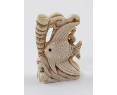 An Edo period ivory netsuke carved in the form of an angelfish amongst coral, signed to a mother of pearl disc inlaid into th