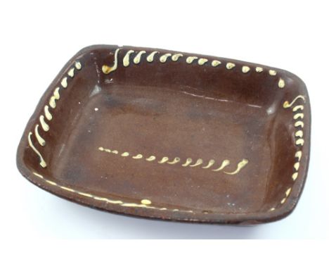 A Barnstaple Pottery style ceramic dish with white slip decoration to a treacle glaze, length 34cm.