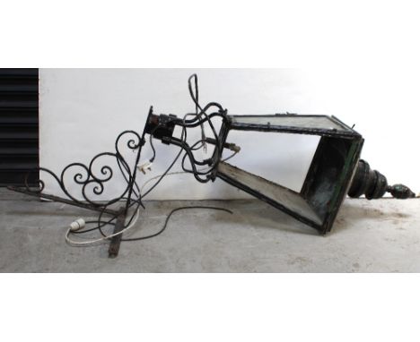 A large Victorian/Edwardian metal lantern/light, converted to electricity, mounted on a black painted wrought iron wall brack