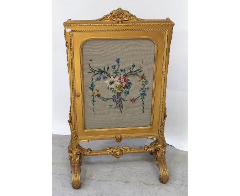 A large ornate gilded fire screen, acanthus leaf and shell decoration above a tapestry floral centre to cross-stretcher and o