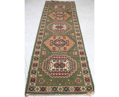 A Persian green ground runner with abstract medallion decoration, approx 80 x 283cm. CONDITION REPORT Some damage to the edge