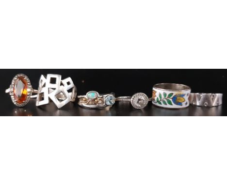 SIX SILVER RINGSof various sizes and designs, including one set with opal and blue topaz, a CZ ring and an enamel decorated e