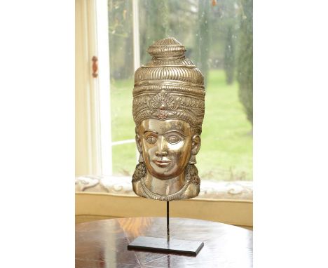 A white metal relief mask,South East Asian, of a female face with an ornate headdress, highlighted with traces of black and r