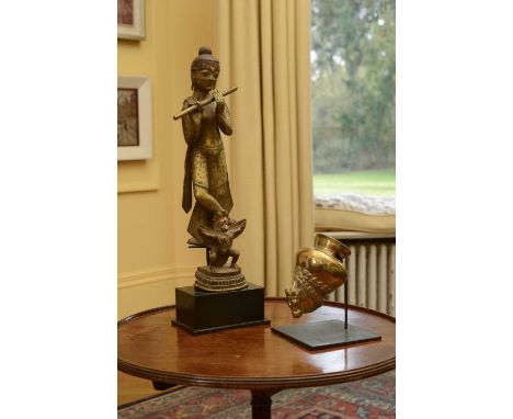 An Indian gilt-bronze figure,19th century, in the form of Krishna playing the flute, with Garuda at his feet,38cm high, on a 