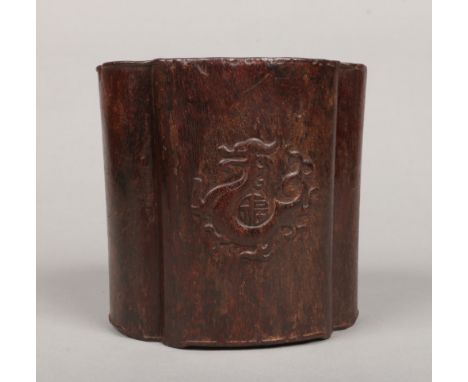 A 19th century Chinese hardwood bitong of quatrefoil shape. Carved in light relief with a dragon and shou character, 14.75cm.