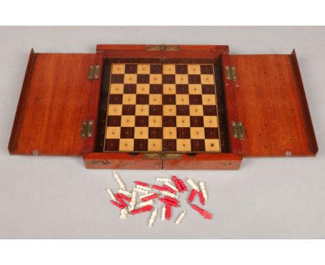 A mahogany folding chessboard with rosewood and maple parquetry inlay along with a carved and polychrome miniature bone chess