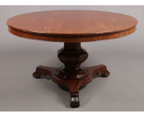 A Victorian mahogany fold over breakfast table. Raised on an octagonal column support over a triform plinth with scrolling fe