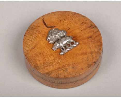 A Victorian circular bur elm trinket box and cover. Surmounted by a silver crest of a wild boar and tree over a torse, 9cm di