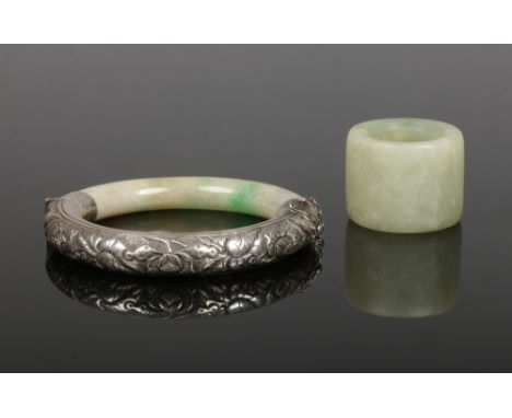 A Chinese silver mounted jadeite bangle chased with flowers along with a celadon jade archers ring. bangle 7.5cm wide.&nbsp;C