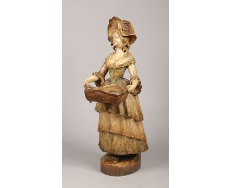 A large Goldscheider terracotta figure of a lady carrying a basket wearing a bonnet and a long flowing dress. Impressed marks