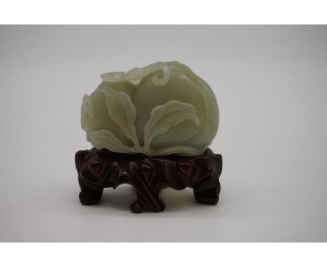 A Chinese carved pale celadon jade group of two peaches,&nbsp;6.5cm wide,&nbsp;on fitted wood stand. 