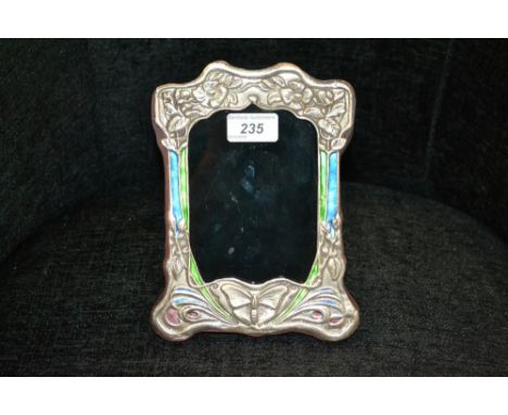 An Art Nouveau style embossed white metal frame, enamel style decoration