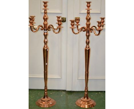 A pair of large rose coloured metal floor standing candelabra, 144cm high