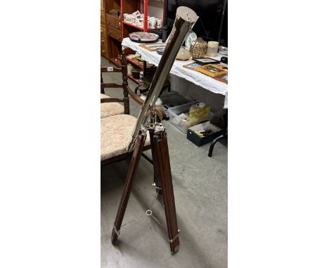 A large chrome plated telescope on a teak tripod base.