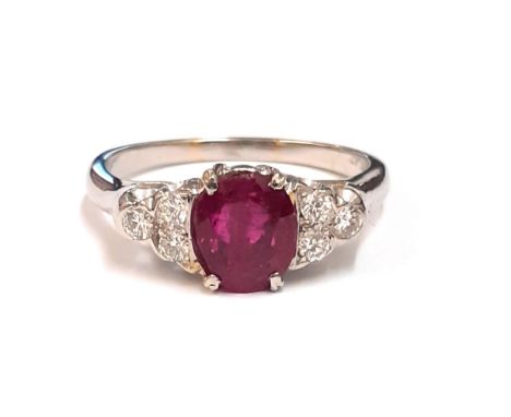 A platinum ring set with an oval cut ruby and brilliant cut diamond set shoulders, (M).