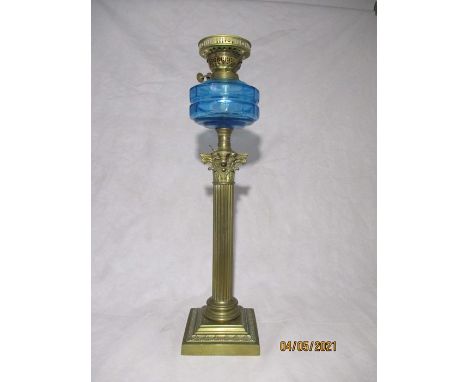 A Victorian oil lamp with brass Corinthian column supporting a blue glass well