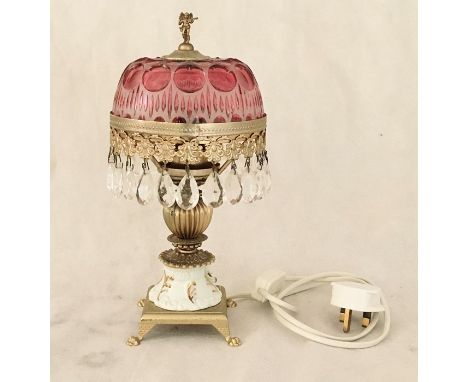 A decorative table lamp with cranberry coloured shade 