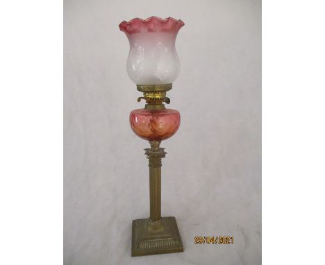 A Victorian oil lamp with Corinthian column with cranberry coloured well and shade